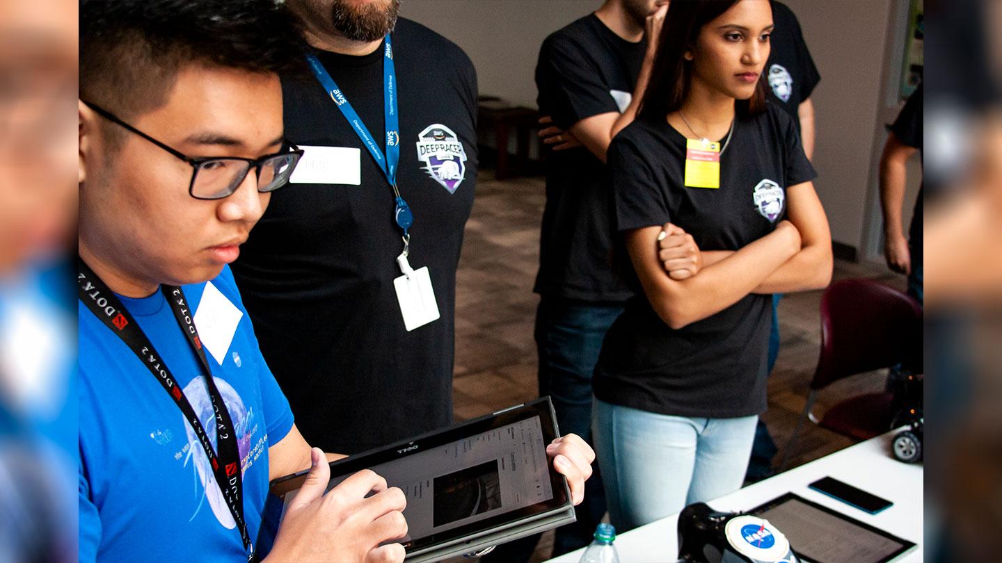 KBR intern Minh Nguyen (left) operates his DeepRacer vehicle using machine-learning models he developed. Nguyen took first in the event