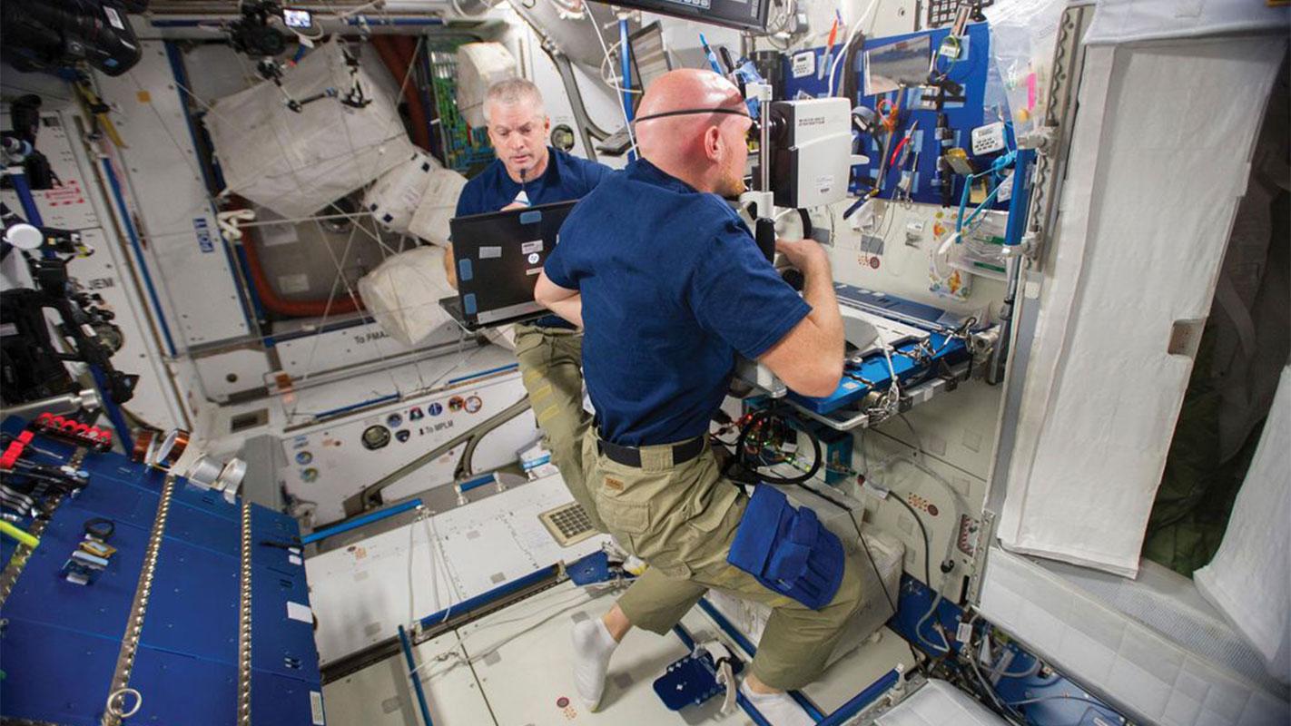 Astronaut Alexander Gerst peers into the Optical Coherence Tomography camera on the ISS.